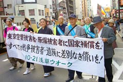 先頭に「東京空襲被害者・原爆被害者に国家補償を！すべての戦争被害者・遺族に差別なき償いを!」の横断幕をかかげて浅草の町をゆく参加者たち。