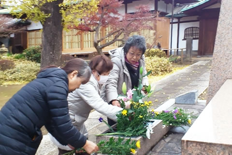 慰霊碑に菊の花を供える事務局員たち。
