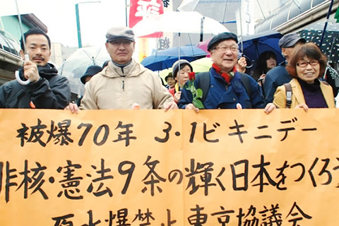 笑顔で町を歩く行進参加者たち。写真に写っているのは「被爆70年 3・1ビキニデー 非核・憲法9条の輝く日本をつくろう 原水爆禁止東京協議会」の横断幕を掲げる人びと