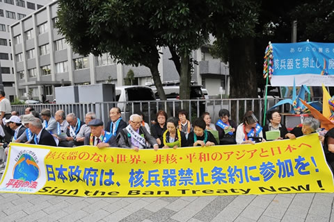 「日本政府は、核兵器禁止条約に参加を！」と書かれた横断幕を持ち、座り込みを行う被爆者たち
