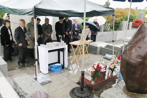 「原爆被害者の墓」の墓石の前に立てられたテントの中で黙祷する参加者