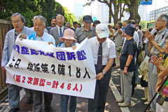 「原爆症認定集団訴訟 本日提訴第3陣18人」の横断幕を掲げ提訴に向かう人たち。