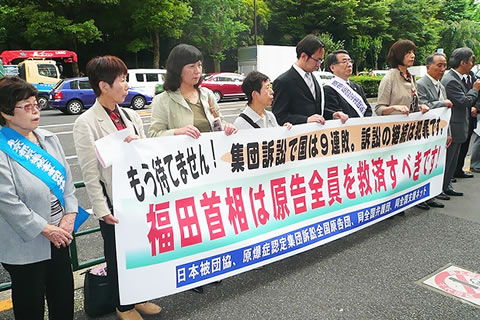 厚生労働省前で「福田首相は原告全員を救済すべきです」など書かれた横断幕を持つ人たち。