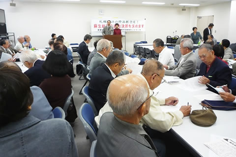 10月2日、並べられた机に着席し、メモを取るなどしながら話を聞く参加者たち。