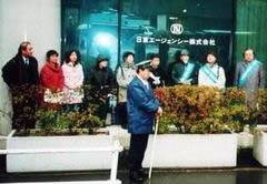 歩道に並ぶ抗議行動参加者らと、威圧するように棒を持って立つ日本の警官。