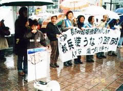 「核兵器使うな」など書かれた横断幕を広げ持つ行動参加者たちと、マイクを使って話す子ども。
