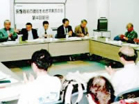 長方形に並べられた机に着席し話し合う参加者たち。