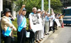アメリカ大使館に向かって並び、、写真パネルを掲げたりこぶしを挙げたりしている抗議行動参加者たち。