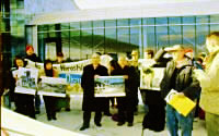 スミソニアン博物館前で、写真などを掲げて立つ被爆者と米市民ら。横断幕を広げ持つ人たちも。