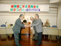 東京原水協の代表から見舞金目録を受け取る藤平会長。