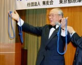 川崎利秋さんが、輪になった長い紐を右手と左手にそれぞれ1つずつ持っている。右手首に、同じひもがもう一つ掛かっている。