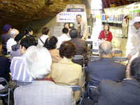 第五福竜丸展示管内、船体のわきに並べられた椅子に座り講演を聞く参加者たち。