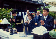 青木恵子被爆者援護係長やその他の人が、しつらえられた祭壇の前で手を合わせている。