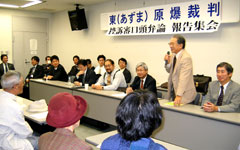 会場前方に並べられた机に弁護士らが座っており、一人が立って参加者に向かって話をしている。