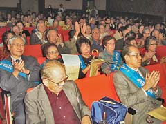 たすきを掛けて客席に座る東友会の参加者たちが拍手をしている。