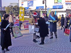 歩道に立つ、署名板を持ったりチラシを手渡す宣伝参加者ら。のぼりや横断幕も掲げられている。