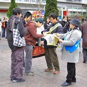 渋谷・ハチ公前で、署名板を持つ支援者と話しながら並ぶ青年たち。