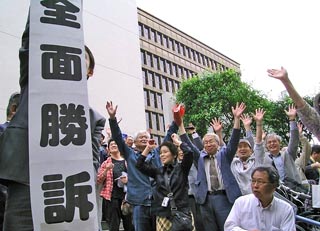 「全面勝訴」の文字を掲げた弁護士と、両手を挙げて喜ぶ被爆者・支援者ら。