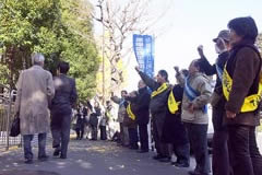 厚生労働省前の歩道に立ち、厚生労働省に向かいこぶしを挙げる参加者たち。