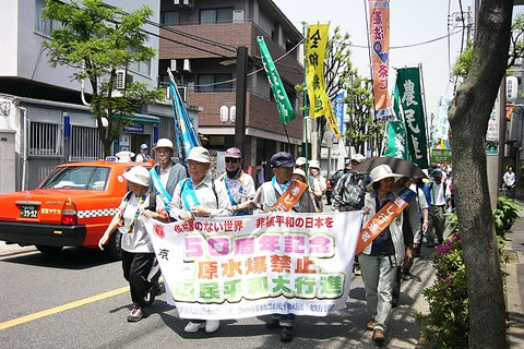 「原水爆禁止国民平和大行進」など書かれた横断幕を持って歩く被爆者たち。