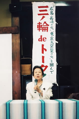 演台のような机で着席し語る米田チヨノさん。その後ろに「三ノ輪deトーク」と書かれたのぼりが立てられている。