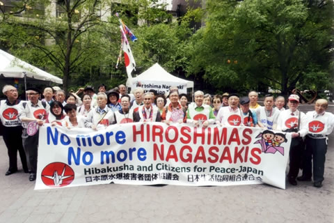 「No more HIROSIHAS No more NAGASAKIS」など書かれた横断幕を広げ持つ代表団の集合写真。