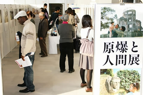 東京原爆展にて。入り口のパネルと、奥へと並ぶ展示に見入る国内外のたくさんのひとたち
