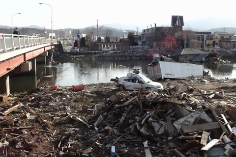 震災被災地、川原はがれきの山、津波で運ばれたトラックや乗用車が置き去りに。