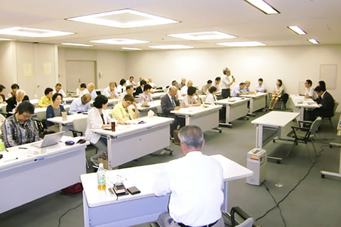 広い部屋に並べられた机に着席する参加者たち。