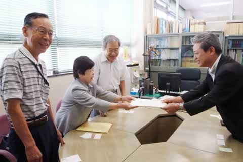 名簿を渡す東友会代表と、受け取る長崎市職員。