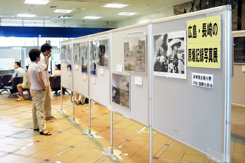 ついたてに展示された、原爆被害を説明するパネルと、それを見る人たち。