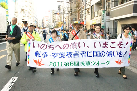 浅草にて「命への償い、いまこそ！戦争・空襲被害者に国の償いを!」の横断幕を先頭に歩く参加者たち。