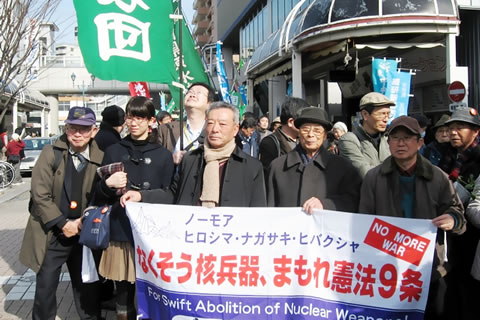 「なくそう核兵器、まもれ憲法9条」と書かれた横断幕を掲げる、焼津駅前からの献花墓参行進。参加者とともに先頭に立つ家島さん。
