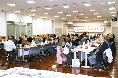 広い部屋、並べられた机に着席した参加者たち。