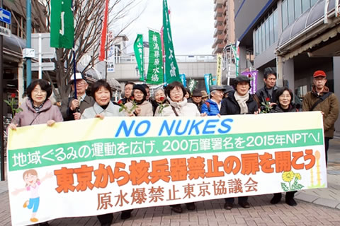 「東京から核兵器禁止の扉を開こう」と書かれた横断幕を持つ人たちを先頭に進む行進。参加した団体ののぼりなどが連なっている。