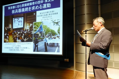 スライドを上映しながら舞台上で活動報告する家島昌志理事