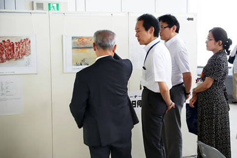 被爆者の描いた絵のパネルの前で説明を聞く東京都福祉保健局長
