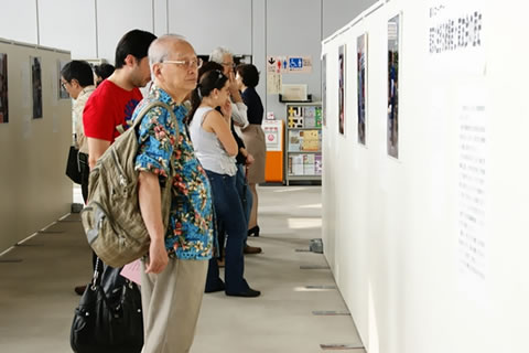 東京原爆展の会場、ついたてに展示されたパネルを見る観光客や見学者たち