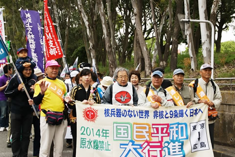 「国民平和大行進」の横断幕を掲げて進む行進。横断幕には「核兵器のない世界 非核と9条輝く日本へ」と書かれている。