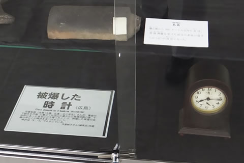 ガラスケースに入れて展示した被爆の現物資料の一部。本体が木製のどっしりとした置き時計は、8月6日広島に原爆が投下された時刻「8時15分」を指したまま止まっている