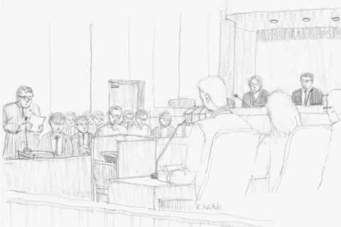 原告(被爆者)側弁護士が弁論している場面。傍聴席、法廷に向かって右側最前列から見た場面。右側手前が国側の席、その奥に裁判官、左手奥に被爆者側の席。左端に弁論している弁護士が描かれている。
