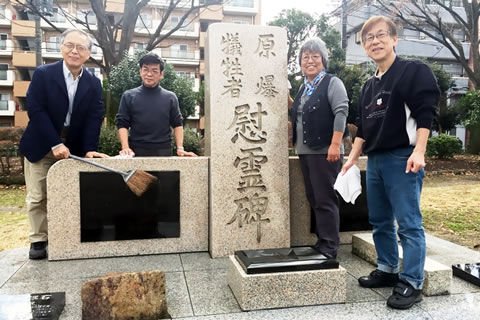 慰霊碑と、慰霊碑を清掃する東友会事務局員4人