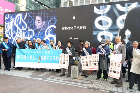 渋谷ハチ公前広場で、国際署名のポスターや横断幕を掲げて訴える被爆者たち。