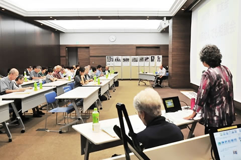 壁一面分の大きさのスクリーンのある広い部屋で行われた相談会、着席してスライドを見る参加者