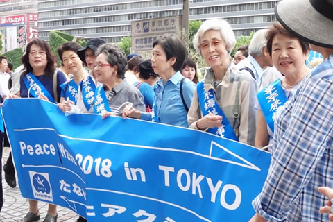 「Peace Wave 2018 in Tokyo たなばたアクション」とかかれた横断幕を持つ、たすきを掛けた被爆者たち