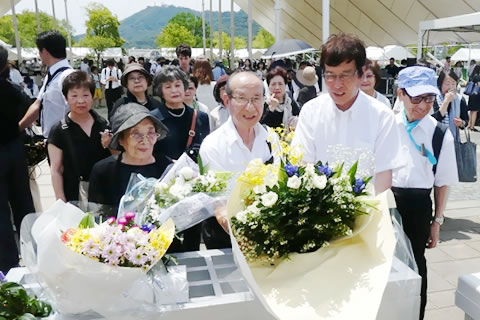 献花台の前に立つ東京の被爆者たち