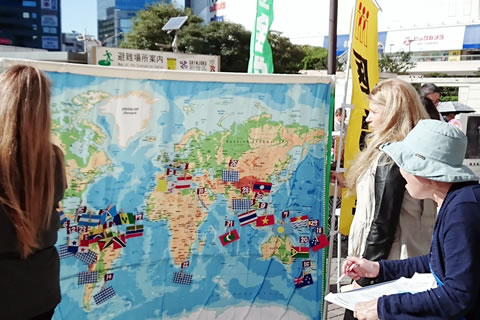 高さ1メートルほどもある世界地図には、核兵器禁止条約を批准した国が国旗が張られて示されている。地図に見入る通行人と、署名板を持って話し掛ける参加者。