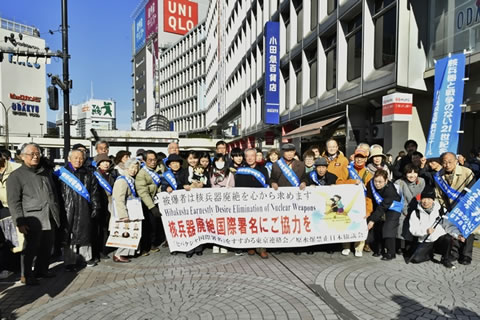 「核兵器廃絶国際署名にご協力を」と書かれた横断幕を持ってならぶ、街頭行動に参加者の集合写真。小田急百貨店前。