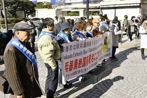 並んで「核兵器廃絶国際署名にご協力を」と書かれた横断幕を持つ被爆者たち。