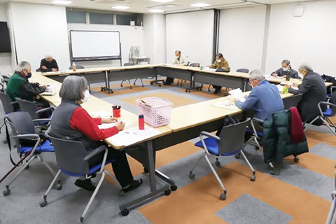3人掛けできる幅の長机が長方形に並べられており、委員が各机に1人ずつ座って話し合いをしている。